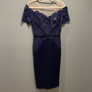 Navy blue mid-length cocktail dress with lace bodice and sheer neckline.